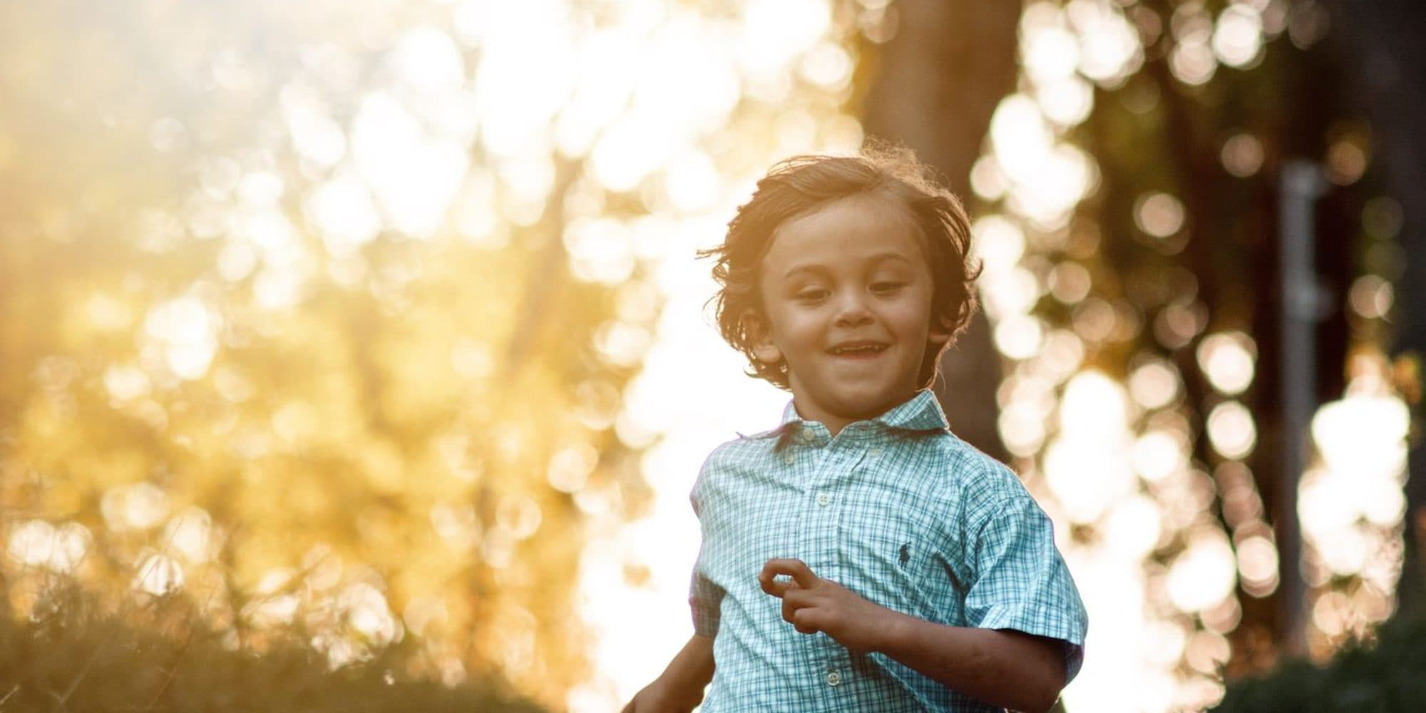 Petit garçon qui court en souriant au coucher du soleil